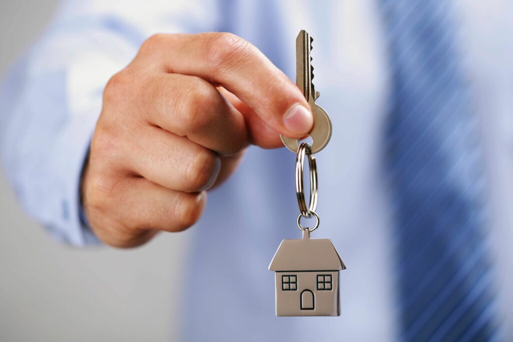a man holding a key with a house kitchain